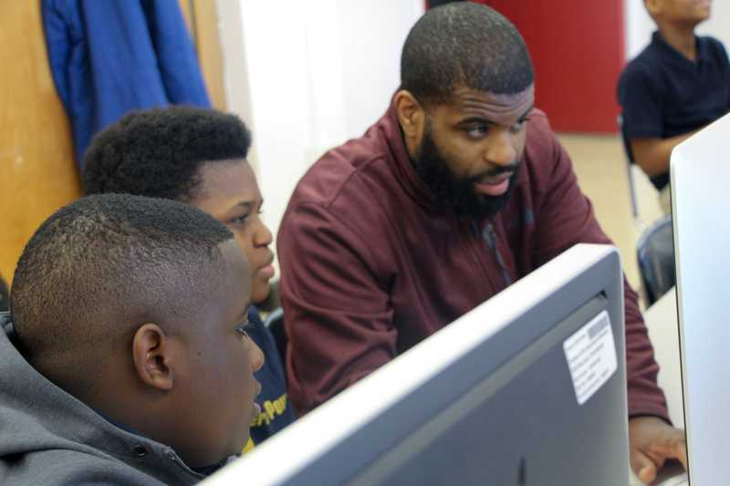 Candid photo of Co-founder Jerome Moore pairing with kids in after school coding program pilot, Ingenious Thought.
